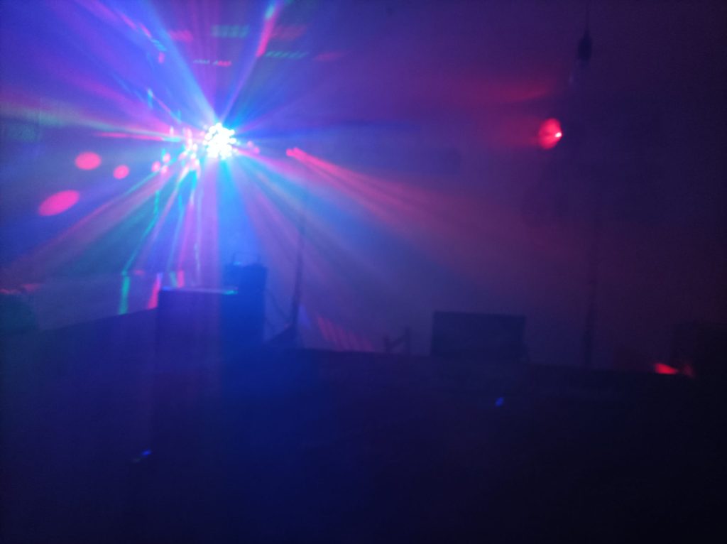 Abendliche Szene mit beleuchteter Tanzfläche und Musik-Equipment.
